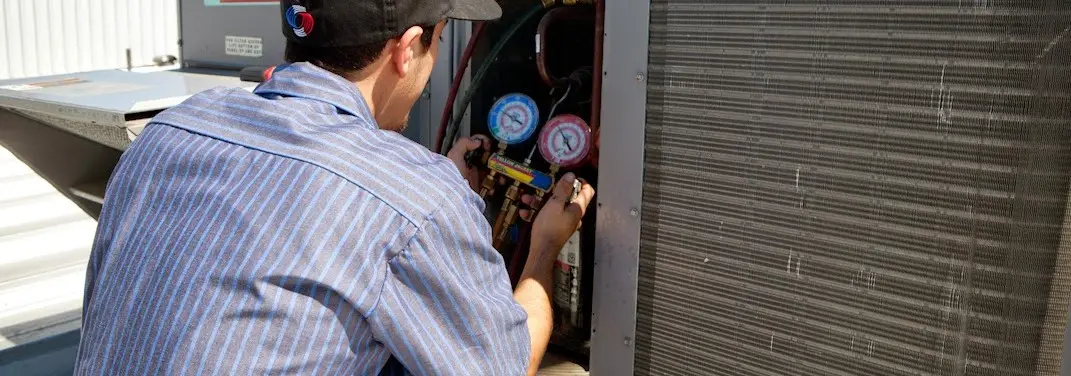 HVAC technician servicing a condenser unit in Mauldin